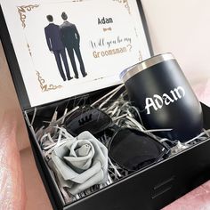 an open black box containing two grooms and a rose with the words adam on it