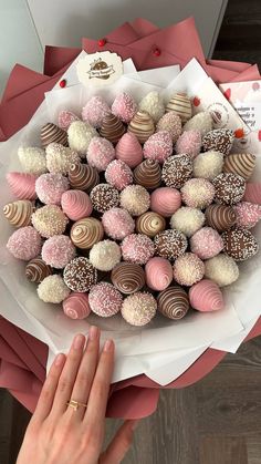 a person holding a bouquet of chocolates with pink and white sprinkles