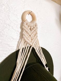 a wooden ring hanging from the side of a wall with white ropes attached to it