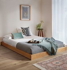 a bed sitting on top of a wooden floor next to a window