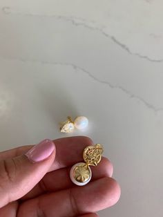 a person is holding two small earrings in their left hand and the other one has a pearl on it