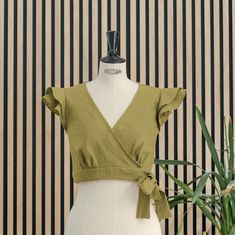 Wrap crop moss green top, short, sleeveless and with two ruffles on the shoulder, it has five pleats under the chest. It closes with a bow that goes around the waist and ties on the left side that we can adjust more or less. Ideal for events, it is a versatile top that we can combine in different looks and styles. Made of premium quality linen, it is a natural, fresh and breathable fabric. Green Non-stretch Summer Top, Chic Cropped Ruffle Crop Top, Green Non-stretch Trendy Blouse, Elegant Fitted Cotton Crop Top, Chic Non-stretch Green Blouse, Chic Fitted Sleeveless Crop Top, Chic Cotton Crop Top, Summer Non-stretch Ruffled Blouse, Elegant Ruffled Crop Top For Spring