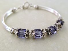 This comfortable bangle bracelet is so pretty in person. Perfect for your bridesmaids on your special wedding day! Can also be given for an anniversary, birthday or mothers day gift among many others... Choose from many colors from the dropdown menu at checkout. ~ 6mm tanzanite swarovski crystal cubes ~ pewter bead caps ~ silver plated tube bead bangles and toggle Click here to return to my shop's homepage: https://www.etsy.com/shop/beadedjewelryforyou?ref=simple-shop-header-name&listing_id= Elegant Purple Bracelets For Wedding, Elegant Purple Wedding Bracelets, Elegant Beaded Bracelets With Birthstone For Wedding, Elegant Beaded Birthstone Bracelets For Wedding, Elegant Wedding Beaded Bracelets With Birthstone, Nickel-free Sterling Silver Bangle For Wedding, Purple Bangle Jewelry For Wedding, Purple Wedding Bracelet Jewelry, Adjustable Purple Bracelet For Anniversary