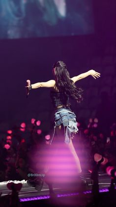 the woman is performing on stage with her arms outstretched in front of an audience at a concert