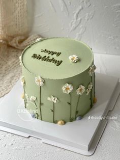 a green birthday cake with white flowers on it