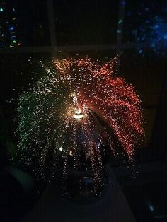 fireworks are lit up in the night sky over a window sill with people looking at them