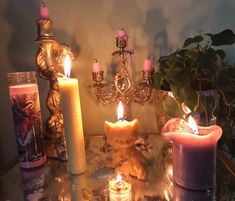 there are many candles on the table and one candle is in front of it with an angel figurine next to it