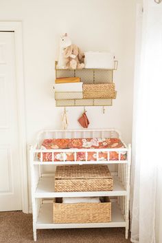 a baby's crib in the corner of a room with baskets on it