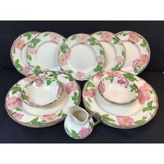 a table topped with lots of white plates and bowls covered in pink flowered designs