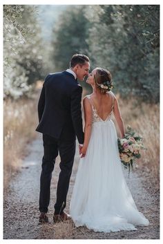 a bride and groom kissing in the middle of an olive tree lined path at their wedding