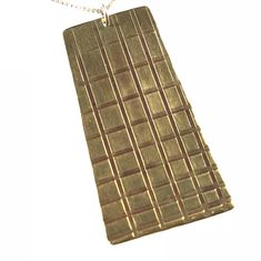 a gold necklace with squares on it is hanging from a silver chain that has a white background