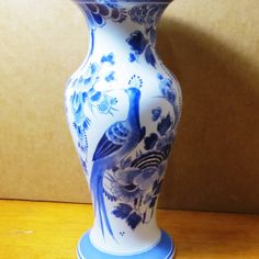 a blue and white vase sitting on top of a wooden table next to a wall