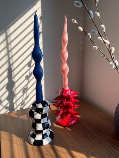 three different colored vases sitting on top of a wooden table