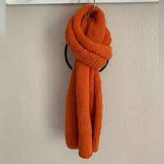 an orange scarf hanging from a hook on a wall