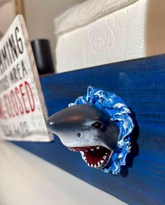 a shark head is on the side of a blue shelf with a sign that says, swimming