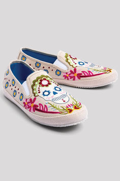 a pair of white shoes with colorful flowers and skulls on the front, side view