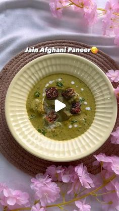 a white bowl filled with food on top of a table next to pink flower petals