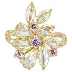 Step into a realm of enchanting beauty with this mesmerizing Abstract Floral Ring, a breathtaking creation by the esteemed designer J. Fine. This piece showcases an artful arrangement of Fancy Yellow Rose Cut Diamonds, totaling 2.81 carats, each stone radiating a warm, golden glow that captures the essence of sunlight. The rose-cut diamonds are delicately set in 18K yellow gold, their unique facets creating a kaleidoscope of light with every movement. Enhancing this floral masterpiece are 0.38 carats of rare Argyle pink diamonds, known for their extraordinary hue and unparalleled rarity. These pink diamonds are meticulously placed to add a touch of romantic allure, contrasting beautifully with the yellow diamonds. Completing the design are additional fancy yellow diamonds, totaling 0.32 ca