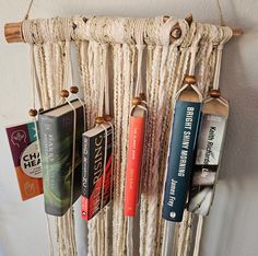 an assortment of books hanging from a rope rack on the wall in front of a white wall