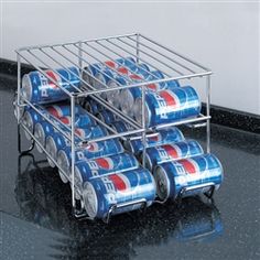 several cans of soda are stacked on top of each other in a metal rack with wheels