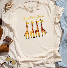 Shirt colors may vary slightly from what is viewed on computer screen. Add a dash of humor and style to your wardrobe with our "Giraffic Jam" T-Shirt! Featuring four geometric-designed giraffes, this shirt is a perfect blend of playful design and modern art. Each giraffe is uniquely crafted with bold, colorful geometric patterns that make them stand out, creating a vibrant and eye-catching ensemble. The clever "Giraffic Jam" text adds a fun twist, making it a perfect conversation starter. Whethe Printed Cotton Novelty Tops, Novelty Printed Cotton Tops, Giraffe Outfit, Zoo Tshirt Ideas, Cricut Zoo Shirt, Animal Shirts Walmart, Animal Kingdom Shirts, Giraffe Shirt, Safari Outfit