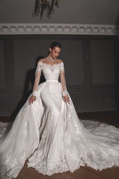 a woman in a wedding dress standing on a wooden floor