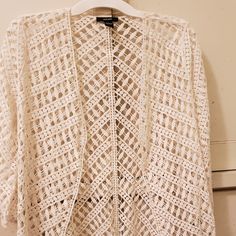 a white crocheted jacket hanging on a hanger