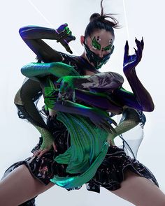 a woman dressed in green and purple is posing with her hands behind her back as if she's dancing