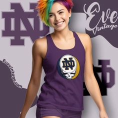 University of Notre Dame Steal Your Face: Showcase Your Fighting Irish Spirit and Love for the Grateful Dead Celebrate your Notre Dame pride and passion for the Grateful Dead with the University of Notre Dame Steal Your Face shirt. This shirt is perfect for students, alumni, and fans who want to express their connection to... Purple Graphic Print Fan Apparel Tops, Collegiate Purple Cotton Tops, Purple Collegiate Cotton Tops, Purple Cotton Collegiate Tops, Purple Graphic Print Top For College, Purple Team Spirit Graphic Print Top, Purple Graphic Print Top With Team Spirit Style, Purple Graphic Print Top For Team Spirit, Steal Your Face