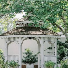 a white gazebo surrounded by potted plants and trees