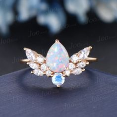 an opal and diamond ring on top of a blue book with flowers in the background