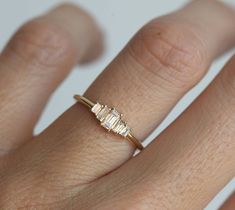 a woman's hand wearing a gold ring with three baguettes on it