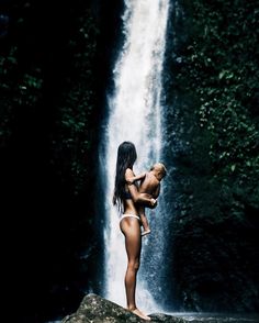 a naked woman standing in front of a waterfall