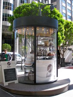 a glass case with plants growing out of it in the middle of a city street