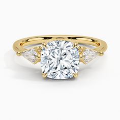 a yellow gold engagement ring with a cushion cut diamond and two side stones on the band