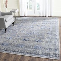 a living room area with a couch, chair and large rug on the hardwood floor