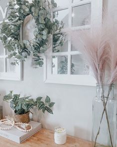 a wooden table topped with vases filled with flowers and plants next to framed pictures