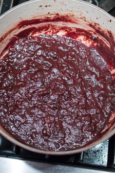 a pan filled with red sauce sitting on top of a stove