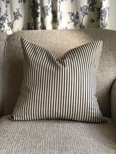 a black and white striped pillow sitting on top of a couch next to a window