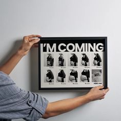 a person holding up a framed poster with the words i'm coming on it