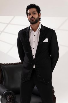 Black tuxedo with placement sequin and cutdana embroidery. Paired with a white shirt and pant.
Components: 3
Pattern: Embroidered
Type Of Work: Sequin, Cutdana
Neckline: Lapel collar
Sleeve Type: Long
Fabric: Terriwool and Cotton, Lining: Poly
Color: Black
Other Details: 
Attached poly lining
Approx. product weight: 3 kgs
Note: Pocket square shown in the image is not for sale.
Occasion: Cocktail and Reception - Aza Fashions Luxury Embellished Fitted Sets, Tailored Embellished Sets For Evening, Tailored Embellished Evening Sets, Luxury Tailored Embellished Sets, Luxury Embellished Tailored Sets, Party Suits With Embellished Notch Lapel, Elegant Fitted Hand Embellished Sets, Tailored Embellished Sets For Party, Festive Sequined Party Suits