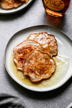 three pancakes on a white plate with syrup and maple syrup in the backgroud