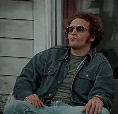 a man with sunglasses sitting on a porch