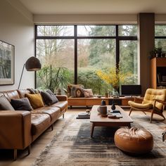 a living room filled with lots of furniture and large windows overlooking the trees in the distance