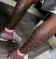 a man with a tattoo on his leg wearing red and white sneakers, holding a tennis racquet