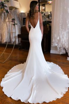 a woman in a white wedding dress standing on a wooden floor with her back to the camera