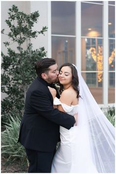 a bride and groom embracing each other in front of a building