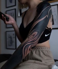 a woman with a tattoo on her arm holding a cell phone