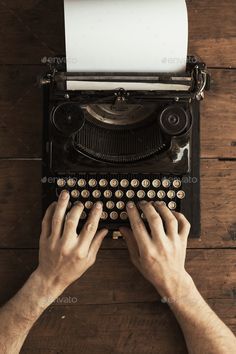 hands typing on an old - fashioned typewriter over a wooden table top view from above