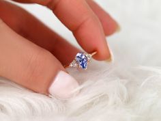 a woman's hand with a ring on her finger and a blue diamond in the middle